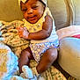 Ariyah is registered to the contest to win money with this photo: baby, infant, child, smiling, headband, bow, blanket, couch, socks, clothing, floral, pattern, indoor, person, cute, happy, skin, face, legs, seated