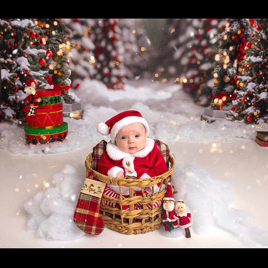 Willowrose is registered to the contest to win money with this photo: baby, basket, celebration, child, christmas, christmas_tree, cute, festive_lights, holiday, holiday_decorations, indoor, ornaments, plush_toys, portrait, red_clothing, santa_hat, smiling, snow, stocking, winter_theme