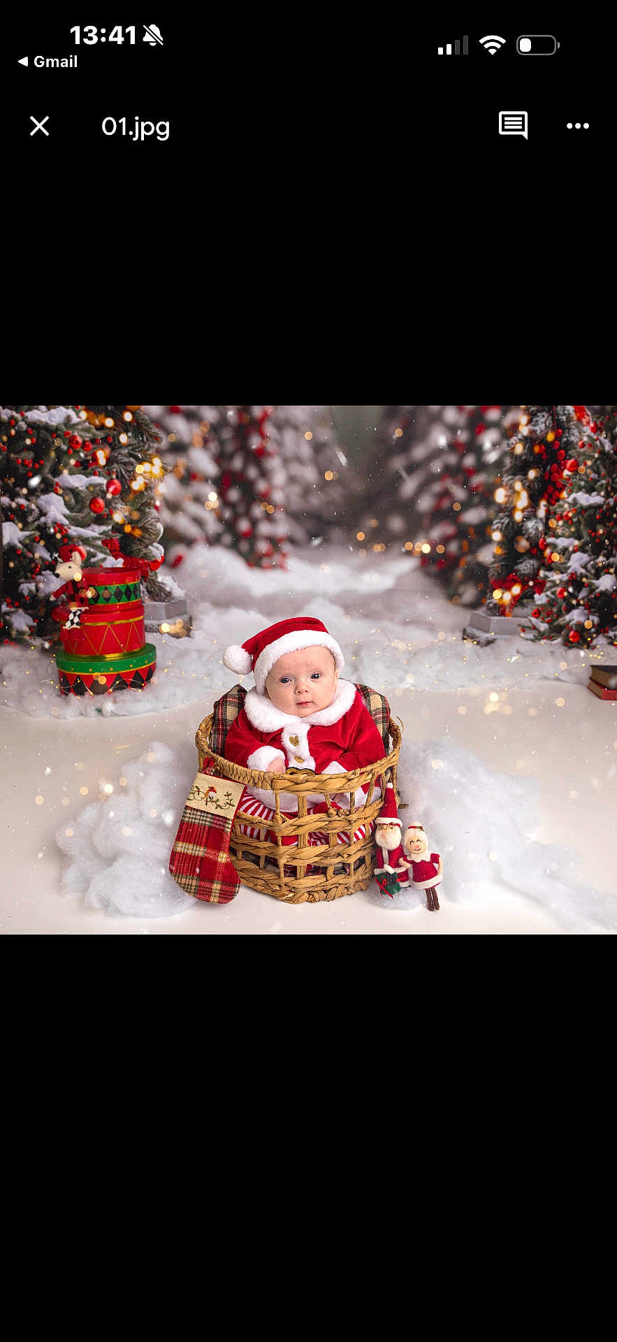 Willowrose is registered to the contest to win money with this photo: baby, child, santa_hat, red_clothing, basket, christmas_tree, holiday_decorations, stocking, snow, festive_lights, ornaments, plush_toys, winter_theme, cute, portrait, indoor, celebration, smiling, holiday, christmas