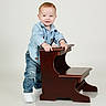 Diago León joined the competition — help win amazing prizes! baby, child, denim, face, furniture, hands, happy, indoors, jeans, portrait, red_hair, reflection, shirt, smiling, sneakers, standing, studio, toddler, white_background, wooden_desk