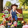 alien, bench, bullseye, buzz_lightyear, child, cowboy_hat, hamm, jessie, mr_potato_head, outdoors, overalls, park, rex, sheriff, slinky_dog, sunlight, toddler, toy_story, toys, woody