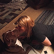 Max is registered to the contest to win money with this photo: dog, woman, indoor, carpet, kiss, love, pet, brown, white, furniture, rug, blonde_hair, floor, cozy, affection, casual_clothing, home, animal, friendship, comfort