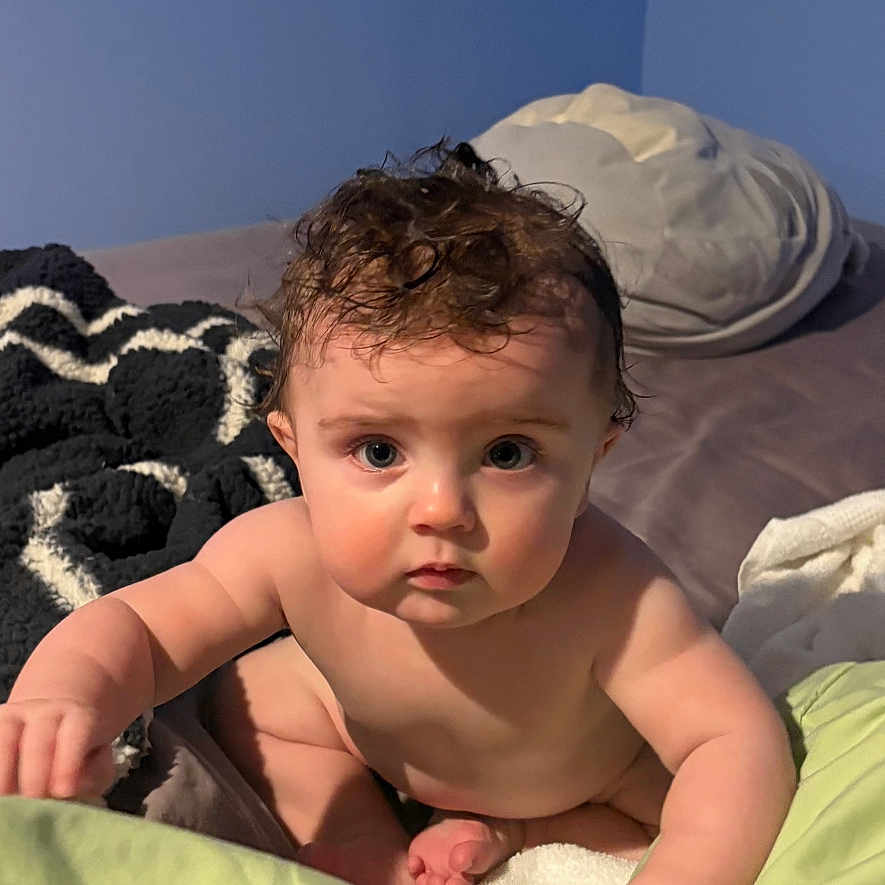 Liam is registered to the contest to win money with this photo: advertisement, baby, bed, bedroom, blanket, bodypart, book, cushion, face, finger, furniture, hand, head, homedecor, indoors, newborn, person, photography, portrait, publication