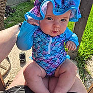 Evelynn is registered to the contest to win money with this photo: baby, child, swimsuit, hat, outdoor, sunlight, grass, fence, lap, legs, hand, playful, curious, summer, cute, skin, person, chair, footwear, patterned_clothing