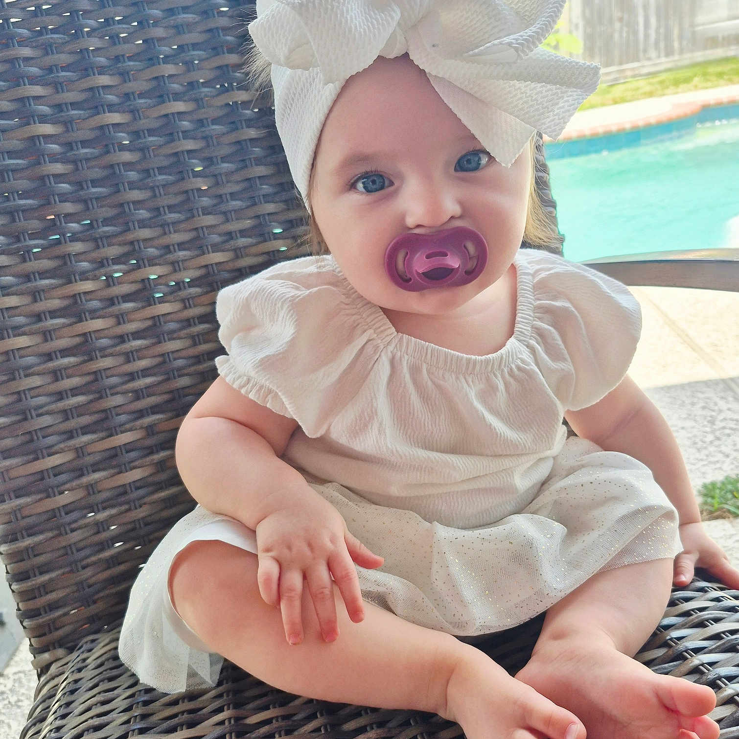 Evelynn is registered to the contest to win money with this photo: baby, blue_eyes, bow, child, cute, daylight, dress, garden, happy, headband, infant, outdoor, pacifier, pool, portrait, relaxing, sitting, summer, white_clothing, wicker_chair