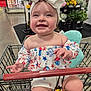 Evelynn is registered to the contest to win money with this photo: baby, child, shopping_cart, headband, smiling, happy, clothing, store, flowers, aisle, red, white, blue, patterned_outfit, indoor, person, cute, infant, seat, retail