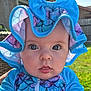 Evelynn is registered to the contest to win money with this photo: baby, child, face, hat, blue, purple, ruffle, bow, eyes, expression, outdoor, sunlight, grass, fence, portrait, close_up, curious, clothing, infant, person