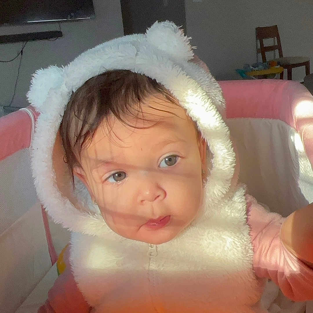 Yaimari joined the competition — help win amazing prizes! baby, child, clothing, curious, cute, eyes, face, fur, headwear, hoodie, indoor, light, person, pink, playpen, plush, portrait, shadow, white, young