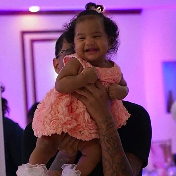 Kali is registered to the contest to win money with this photo: baby, baby_toddler_clothing, cheek, comfort, dress, face, finger, formal_wear, gesture, hairstyle, happy, joy, person, pink, purple, shoulder, skin, smile, thigh, thumb