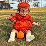 toddler, child, pumpkin, orange_dress, hat, grass, outdoor, curly_hair, socks, fall, cute, playful, nature, autumn, baby, sitting, smile, park, daylight, portrait