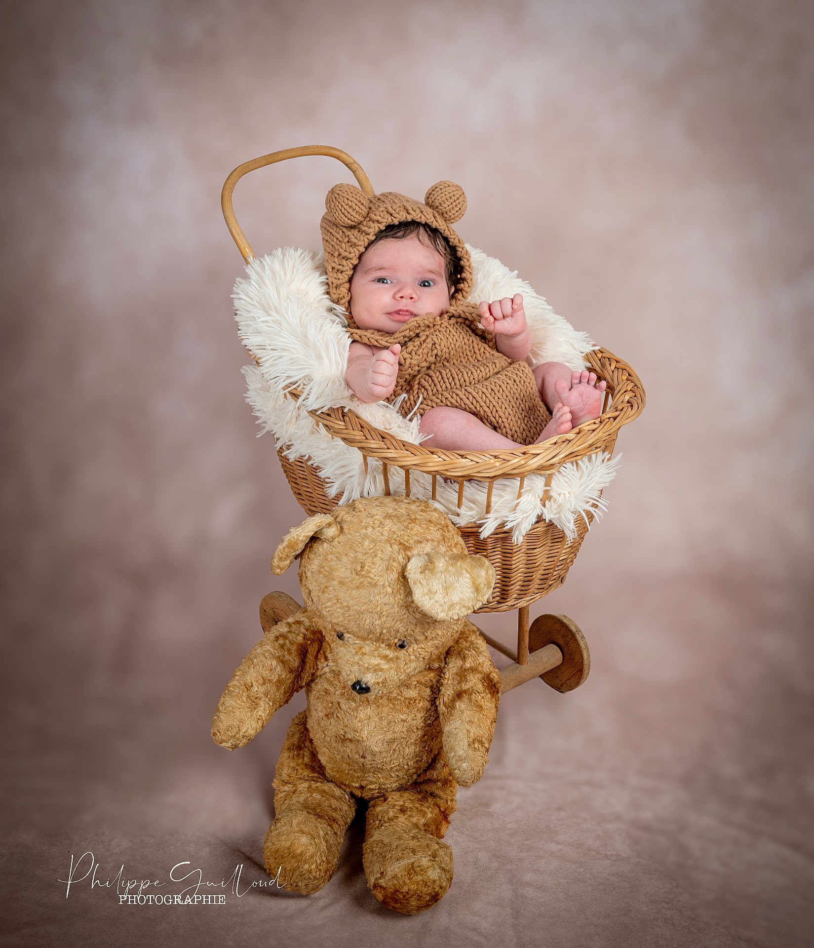 Myliano participe au concours pour gagner de l'argent avec cette photo : baby, infant, knitted_clothing, bear_ears, wicker_basket, plush_toy, teddy_bear, soft_fabric, portrait, studio_photography, child, cute, smiling, cozy, warm_lighting, neutral_background, fuzzy_texture, seated, small_hands, baby_feet