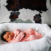 Oaklynn is registered to the contest to win money with this photo: baby, newborn, sleeping, pink_outfit, blanket, basket, fur_rug, cowhide, soft_texture, cozy, indoor, infant, peaceful, cute, child, portrait, resting, warm, comfortable, closeup