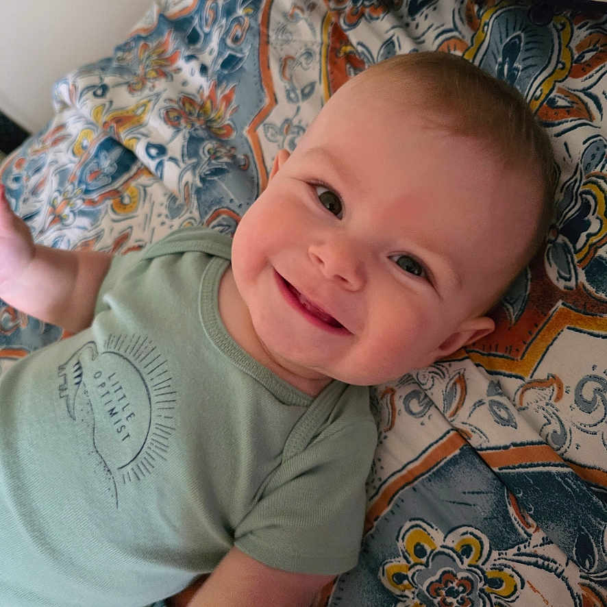 Gabriel is registered to the contest to win money with this photo: baby, bed, bedroom, bodypart, clothing, cushion, face, finger, furniture, hand, happy, head, homedecor, indoors, person, photography, portrait, room, smile, t_shirt