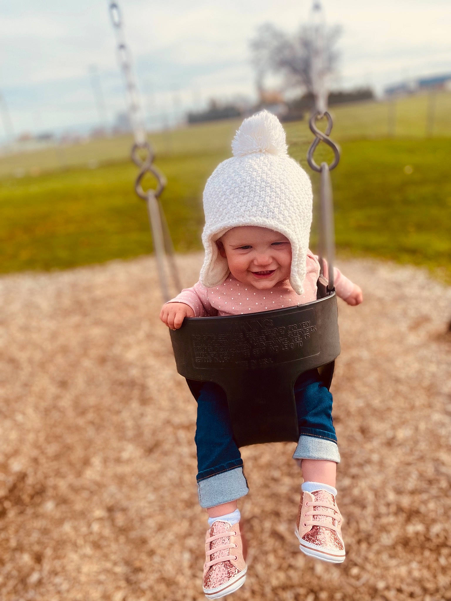 Cali is registered to the contest to win money with this photo: baby, baby_toddler_clothing, cap, eye, fun, grass, happy, headgear, headwear, human_body, joy, leisure, outdoor_play_equipment, outerwear, people_in_nature, person, recreation, sky, smile, swing