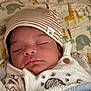 baby, sleeping, hat, striped_hat, blanket, animal_pattern, elephant, giraffe, button, cute, infant, cozy, soft, child, face, peaceful, indoors, closeup, newborn, clothing