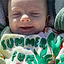baby, infant, smiling, blanket, sweater, colorful_clothing, embroidery, green, white, soft_texture, cute, happy, hands, outdoor_light, face, head, child, cozy, pattern, nature_theme
