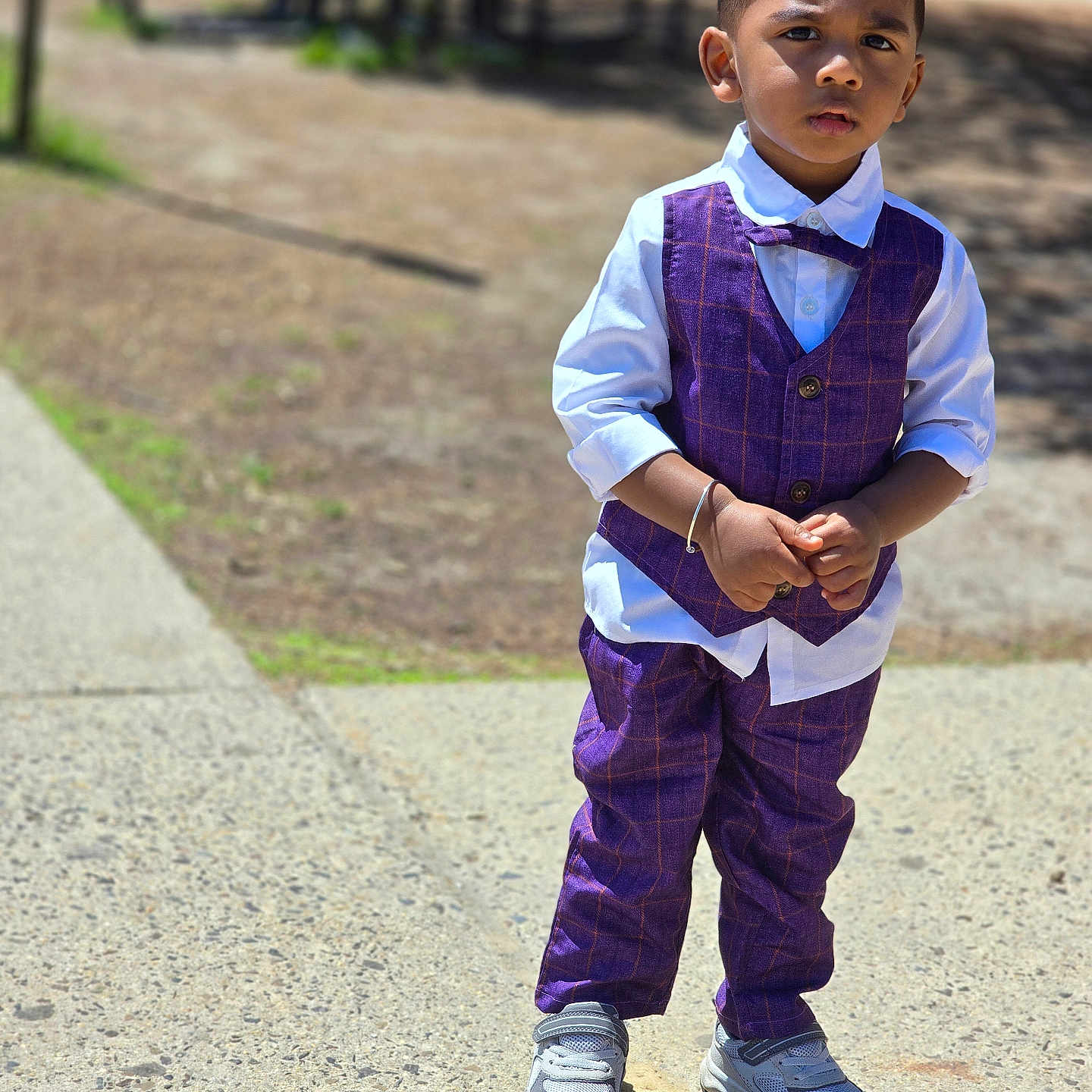 Shashtik joined the competition — help win amazing prizes! child, boy, outdoor, sunny, vest, bow_tie, purple_clothing, pants, shoes, standing, serious_expression, sidewalk, park, bench, daylight, portrait, young_child, casual, fashion, person