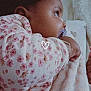 baby, pacifier, blanket, floral_pattern, close_up, infant, child, sleepwear, soft_texture, cute, cozy, warm, portrait, side_view, hand, bracelet, indoors, young_child, comfort, love