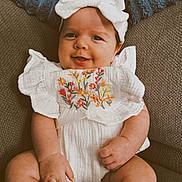 Wren joined the competition — help win amazing prizes! baby, infant, smiling, white_clothing, headband, floral_embroidery, couch, blue_cushion, cute, happy, portrait, child, indoors, seated, closeup, skin, hand, face, young, comfort
