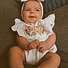 Wren is registered to the contest to win money with this photo: baby, infant, child, couch, headband, white_outfit, floral_embroidery, cute, smiling, sitting, indoor, plush_pillow, cozy, portrait, small_hands, legs, comfortable, soft_texture, happy, adorable