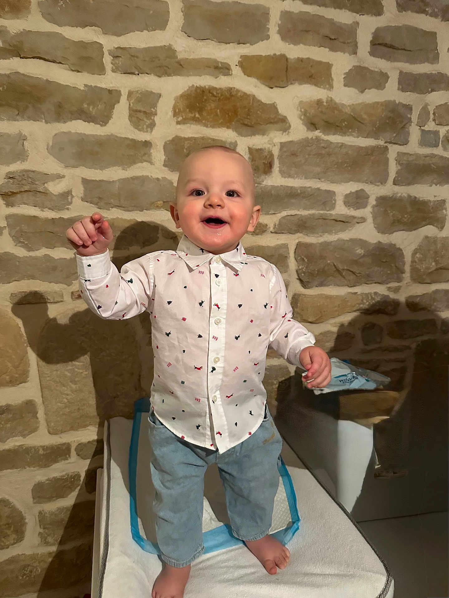 Léo a rejoint le concours — aidez-le/la à gagner de superbes lots ! toddler, child, boy, standing, shirt, jeans, barefoot, indoor, stone_wall, smiling, happy, person, clothing, furniture, cushion, shadow, home, casual, portrait, cute