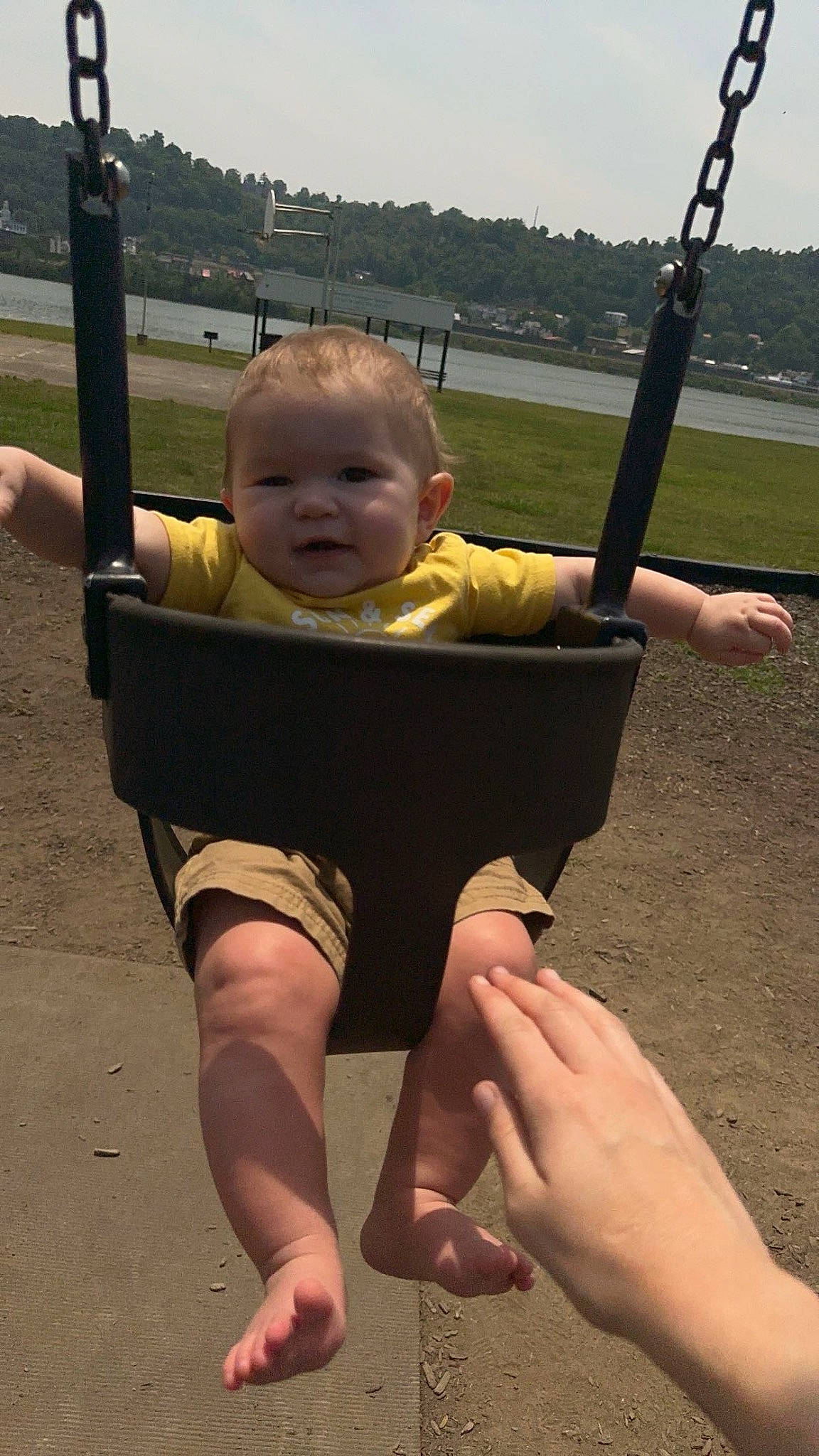 Bryson is registered to the contest to win money with this photo: baby, baby_toddler_clothing, child, city, finger, fun, gesture, grass, hand, happy, leisure, outdoor_play_equipment, person, recreation, shade, sky, standing, summer, swing, thumb