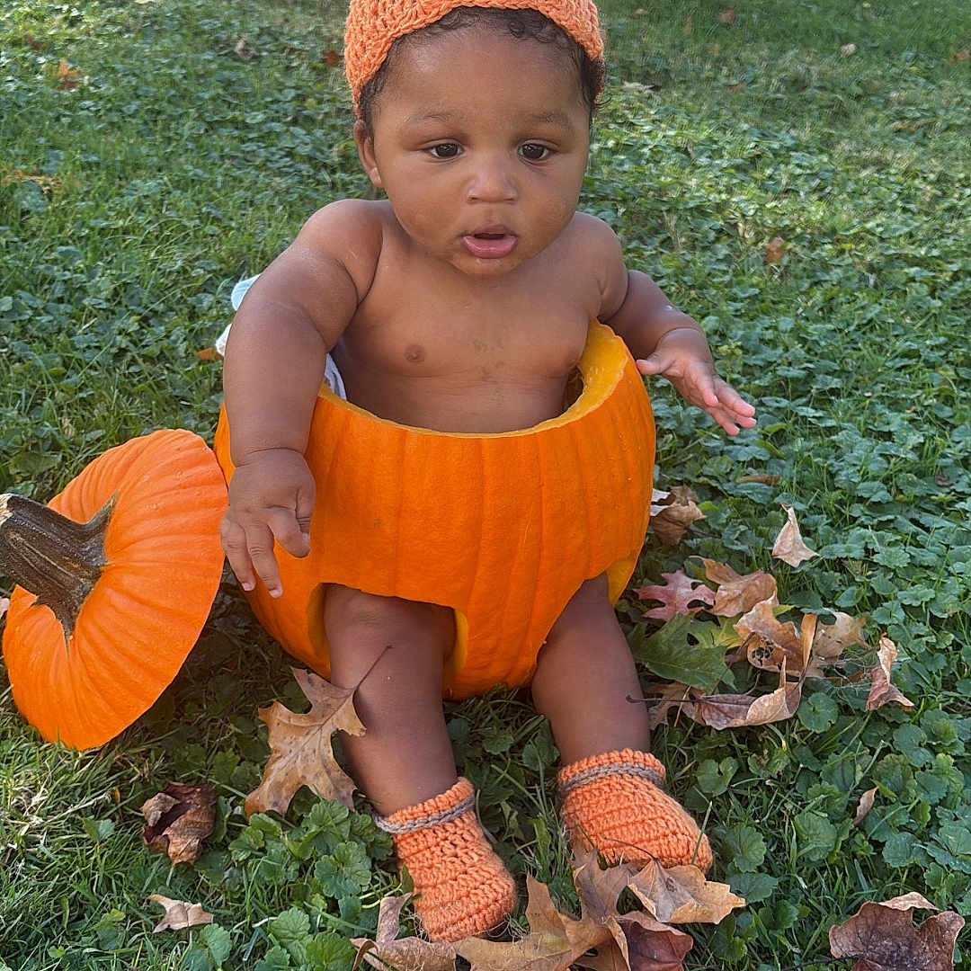 Javan is registered to the contest to win money with this photo: autumn, baby, baby_boy, child, costume, cute, fall_leaves, grass, harvest, holiday, knit_booties, knit_hat, leaf_litter, nature, orange, outdoor, playful, pumpkin, seasonal, sitting