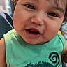 child, toddler, smiling, face, green_shirt, tank_top, indoors, cute, happy, baby, person, portrait, hair, skin, closeup, expression, young_child, chameleon_graphic, clothing, casual