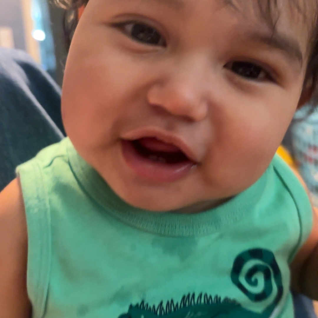 Asher joined the competition — help win amazing prizes! child, toddler, smiling, face, green_shirt, tank_top, indoors, cute, happy, baby, person, portrait, hair, skin, closeup, expression, young_child, chameleon_graphic, clothing, casual