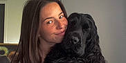 Tiamo participe au concours pour gagner de l'argent avec cette photo : animal, black_dog, casual_clothing, companion, couch, curly_hair, dog, face, friendly, furniture, home, hugging, human, indoor, long_hair, pet, portrait, relaxed, smiling, woman