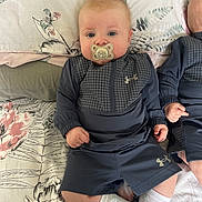 Riley joined the competition — help win amazing prizes! baby, pacifier, blue_eyes, under_armour, sportswear, bedspread, floral_pattern, infant, child, cute, lying_down, white_socks, hands, face, head, soft_lighting, indoor, twin, sleepwear, pillow