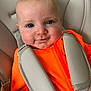 Riley is registered to the contest to win money with this photo: baby, child, face, blue_eyes, car_seat, orange_clothing, smile, infant, safety_harness, cute, skin, head, person, seat, straps, young_child, indoor, closeup, comfortable, happy