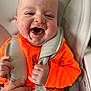 John is registered to the contest to win money with this photo: baby, child, smiling, orange_clothing, high_chair, happy, face, hands, infant, closeup, seatbelt, person, cute, indoor, sitting, joyful, expression, strap, head, skin