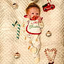 baby, infant, blanket, christmas, holiday, ornaments, candy_cane, pacifier, bib, toy_truck, santa_ornament, plush, cute, sleepwear, festive, decorations, holiday_season, newborn, soft_texture, lying_down
