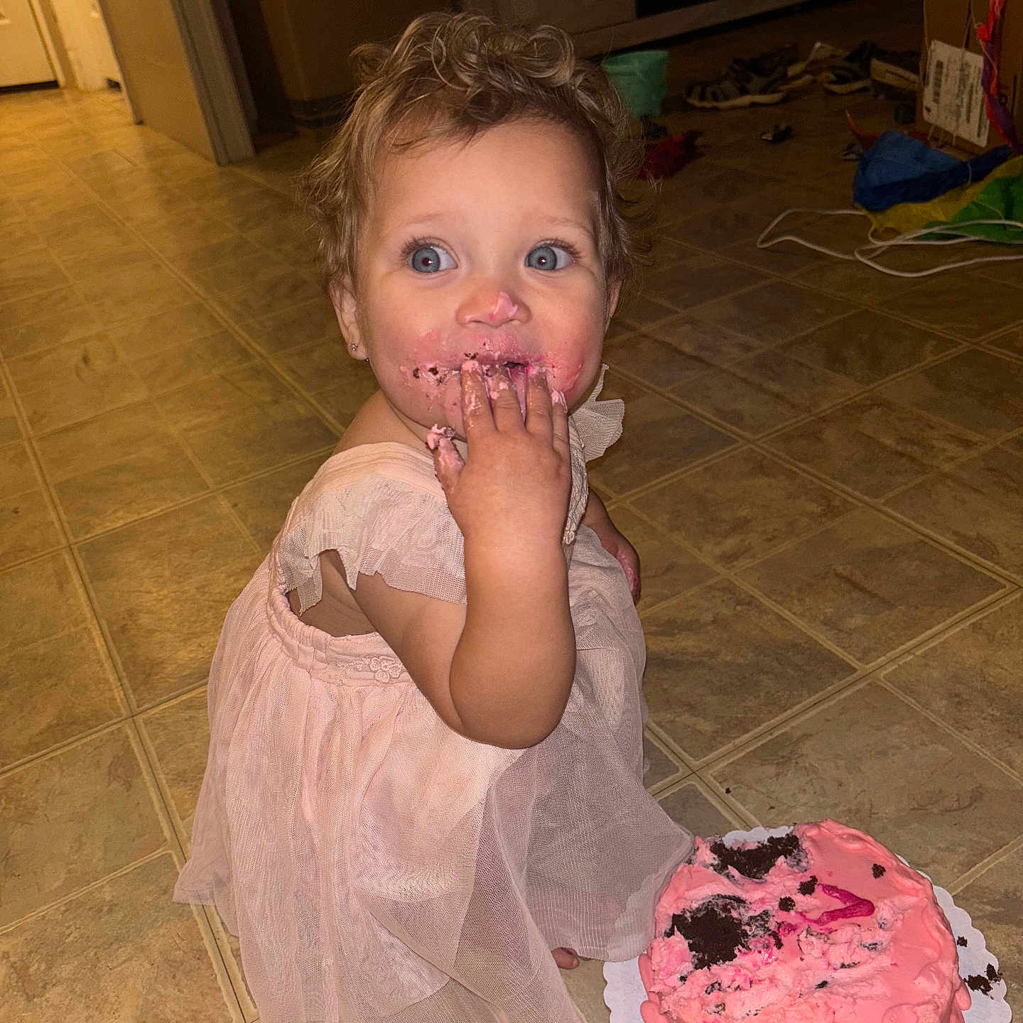 Rosilee joined the competition — help win amazing prizes! blue_eyes, cake, celebration, child, curly_hair, cute, dress, floor, food, fun, happy, home, indoors, messy, person, pink_frosting, playful, portrait, smiling, toddler