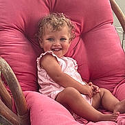Rosilee joined the competition — help win amazing prizes! baby, barefoot, child, curly_hair, cushion, cute, daylight, face, happy, outdoor, person, pink_chair, plush, portrait, relaxed, sitting, smiling, summer_clothing, toddler, wooden_frame