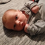 Gabriel Michael joined the competition — help win amazing prizes! baby, infant, face, person, clothing, grey_outfit, lying_down, fist, skin, head, eyes, indoors, soft_surface, texture, cute, young_child, portrait, expression, newborn, sleepwear