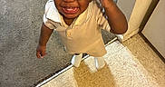 Jamir is registered to the contest to win money with this photo: toddler, child, sunglasses, smiling, indoor, carpet, tile_floor, rug, patterned_rug, clothing, short_sleeves, happy, standing, hand_up, person, floor, wall, corner, home, baby