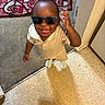 toddler, child, sunglasses, smiling, indoor, carpet, tile_floor, rug, patterned_rug, clothing, short_sleeves, happy, standing, hand_up, person, floor, wall, corner, home, baby