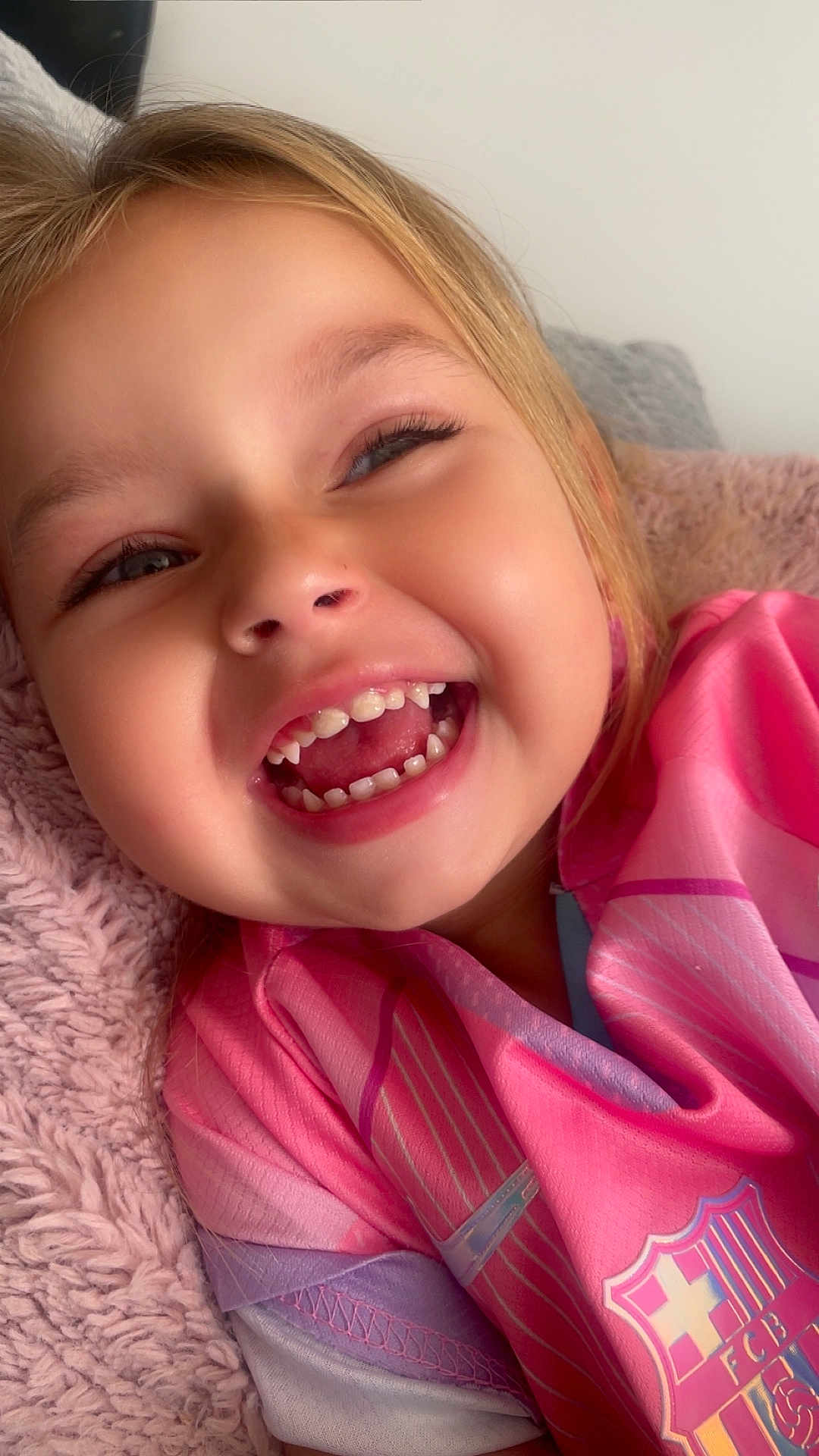 Aya participe au concours pour gagner de l'argent avec cette photo : child, smiling, laughing, face, teeth, pink_clothing, purple_clothing, blanket, closeup, happy, cute, person, young, indoor, portrait, head, skin, eyelashes, nose, mouth