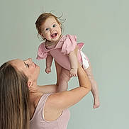 Emiliya is registered to the contest to win money with this photo: baby, woman, child, smile, pink_clothing, long_hair, happy, lifting, studio, portrait, arm, skin, person, holding, cute, joy, infant, sleeveless_top, female, background