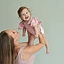 baby, woman, child, smile, pink_clothing, long_hair, happy, lifting, studio, portrait, arm, skin, person, holding, cute, joy, infant, sleeveless_top, female, background