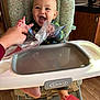 Ezekiel is registered to the contest to win money with this photo: baby, cabinet, clothing, countertop, expression, foot, graco, hand, happy, high_chair, indoor, infant, kitchen, person, plastic_bag, playful, seat, smiling, table, wood_floor