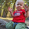 toddler, child, dirt, hands, red_shirt, green_pants, kneeling, forest, trees, outdoor, daylight, play, messy, person, nature, young_child, casual_clothing, short_hair, ground, curious