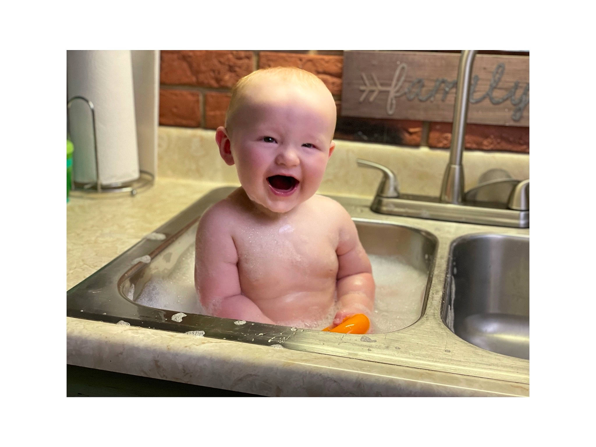 Eli is registered to the contest to win money with this photo: baby, baby_bathing, baby_laughing, baby_products, baby_toddler_clothing, bathing, cheek, child, face, fun, happy, head, jaw, laugh, person, photo_caption, rectangle, sitting, sleeve, smile