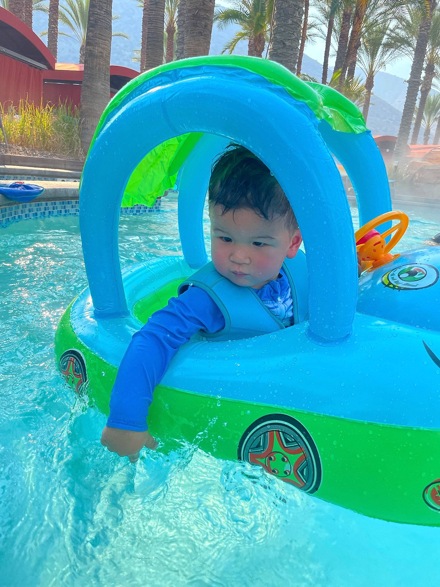 Clark is registered to the contest to win money with this photo: aqua, azure, baby, baby_float, baby_toddler_clothing, blue, child, fluid, fun, games, inflatable, leisure, outdoor_recreation, person, personal_protective_equipment, plant, play, recreation, toddler, tree