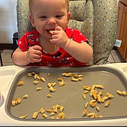 Khloe joined the competition — help win amazing prizes! toddler, child, high_chair, pancakes, food, eating, red_shirt, kitchen, baby, smiling, face, person, seat, furniture, foot, hand, tray, snack, indoors, cute