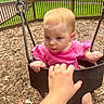 toddler, child, swing, playground, pink_shirt, hand, outdoor, wood_chips, fence, greenery, daylight, curious, baby, person, seat, park, young_child, play, casual_clothing, nature