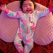 Navaya joined the competition — help win amazing prizes! baby, smiling, onesie, flamingo, pink, cushion, red_background, curly_hair, happy, infant, sleepwear, soft_texture, lying_down, child, cute, joyful, expressive_face, comfort, patterned_blanket, indoors