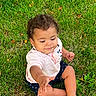 baby, child, infant, sitting, grass, outdoor, park, portrait, curly_hair, brown_hair, barefoot, smiling, curious, reaching, hand, pink_shirt, shorts, lawn, leaves, natural_light